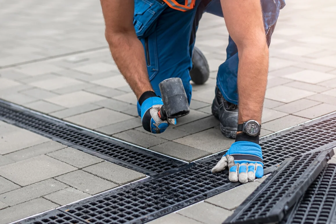 Person baut mit Gummihammer eine Regenrinne ein.